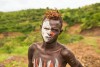 Young boy from the African tribe Mursi with traditionally painted face in Mago National Park